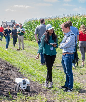 Two people talking next to a robot at Grand Farm.