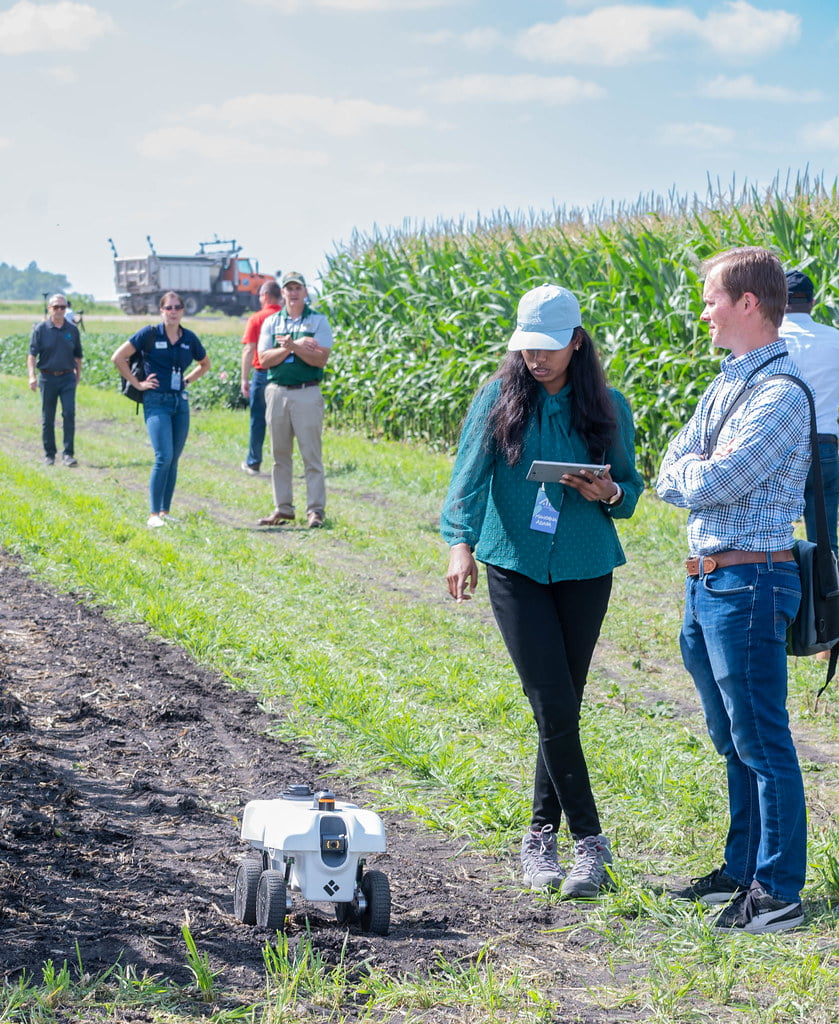 Two people next to an agriculture robot.